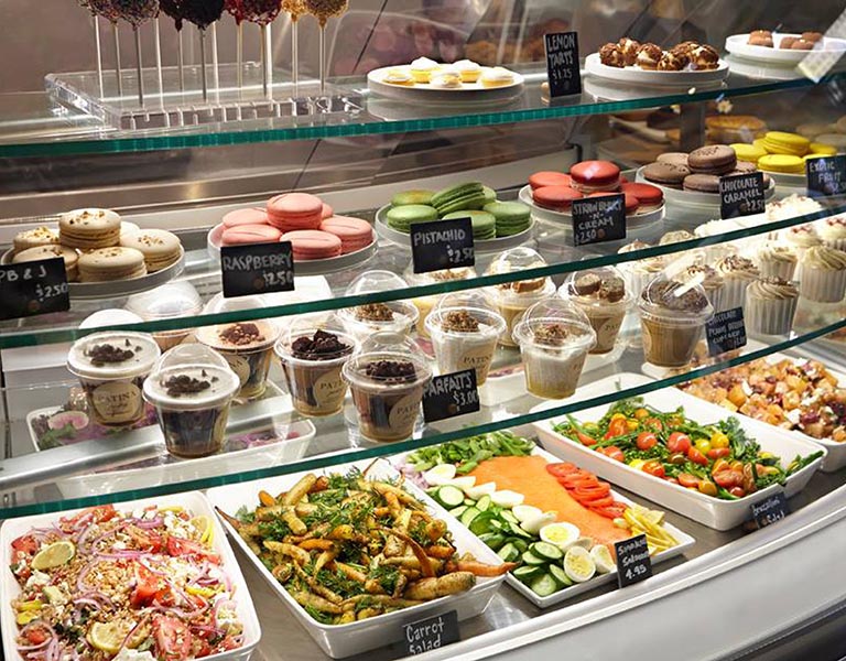 Food service counter cases featuring salads, smoked salmon, and desserts
